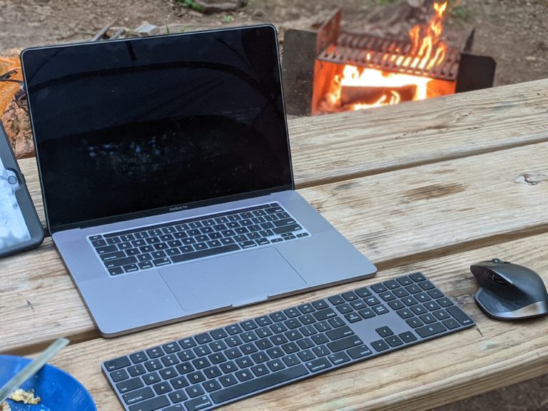 Laptop on a picnic bench by a fire